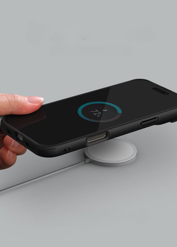 A hand holds an iPhone 16 Pro Max in a Shockproof Slim Fit iPhone 16 Pro Max Case with MagSafe, Dual-Layer Protection, and Camera Cover above a wireless charging pad, showing a charging status of 74% on the phone screen. The case also features an Anti-Slip Grip for added security.