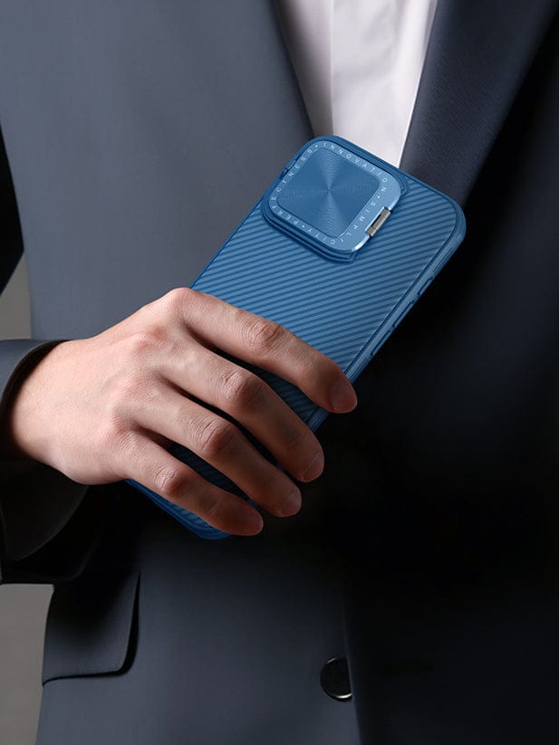 A person dressed in a dark suit holding an iPhone 16 Pro Max with a Shockproof Slim Fit Case featuring a blue textured, anti-slip grip and a squared camera cover.