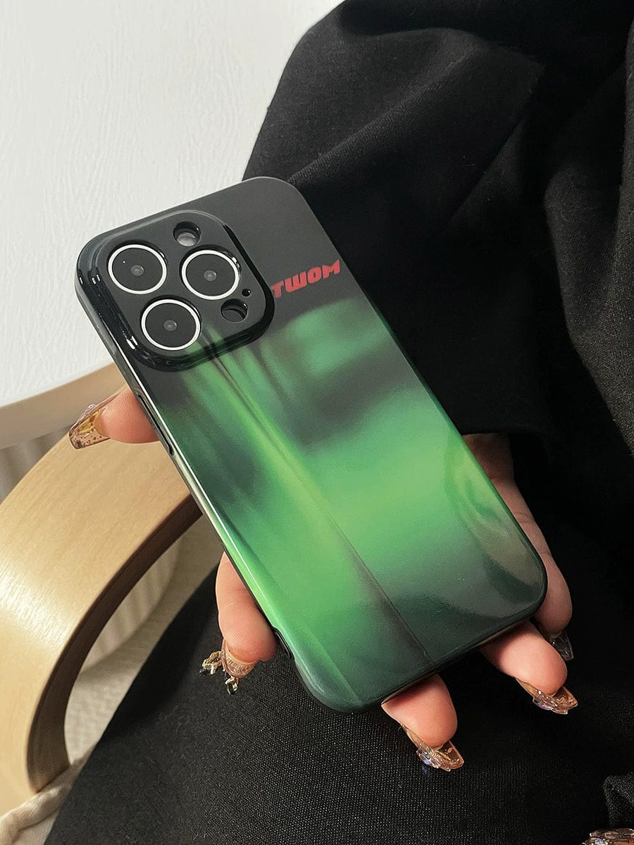 A person holding an iPhone 16 Pro Max with the Aurora Green Gradient Case, showcasing a sleek Northern Lights design. The phone features a triple camera setup and a red logo on the case. The individual has long, decorated nails and is dressed in black clothing.