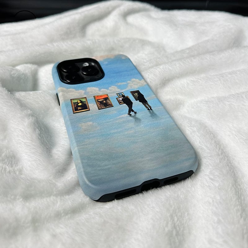 A smartphone with the "Surreal Art Gallery iPhone 16 Pro Max Case - Dreamy and Protective" features artwork depicting two people walking across a reflective, water-like surface under a cloudy sky. Paintings and frames float in the air ahead of them. The phone rests on a soft, white fabric background, blending art and technology seamlessly.