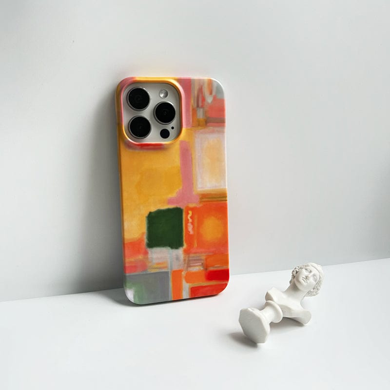 A Modern Abstract Color Block iPhone 16 Pro Max Case - Vibrant Artistic Design with Full Protection, showcasing an abstract, colorful pattern with geometric shapes in orange, green, yellow, and white, is leaning against a plain light background. In front of the phone lies a small white bust statue positioned horizontally.