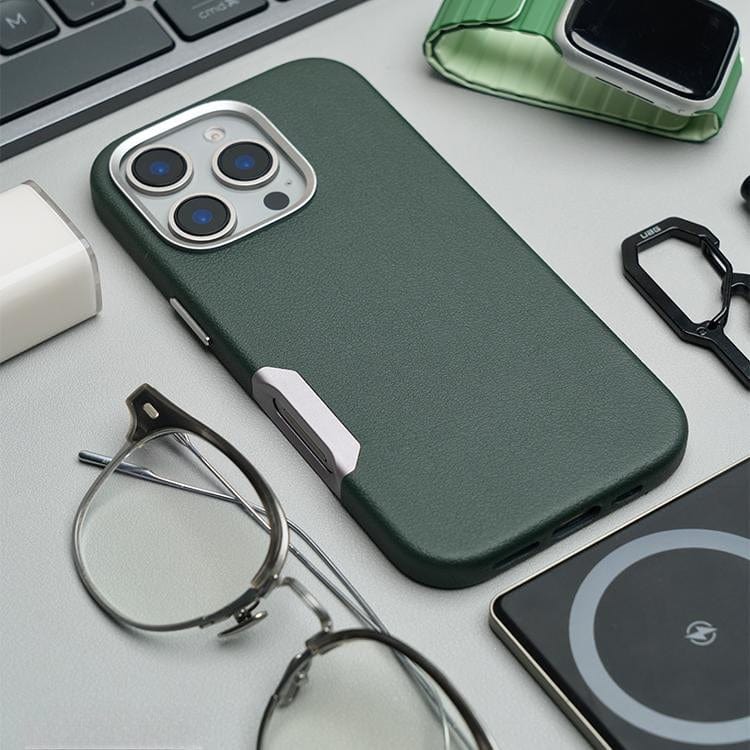 An iPhone 16 Pro Max protected by a Leather Case featuring Aluminum Alloy Buttons, MagSafe Compatibility, and a Raised Camera Frame sits elegantly on the desk, amidst glasses, a pen, a smartwatch, and a wireless charger. Its seamless design fits perfectly into the contemporary workspace.