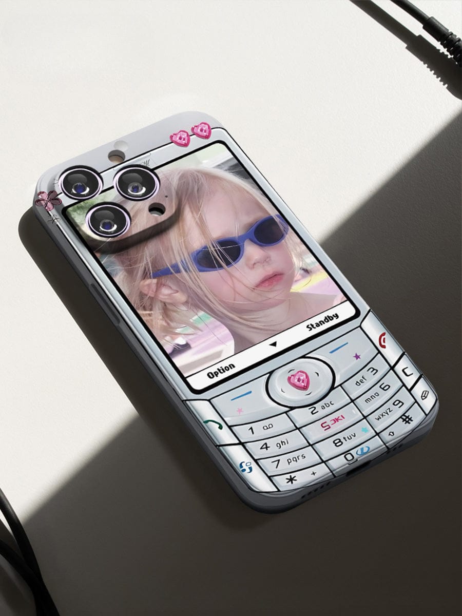 A modern smartphone with three rear cameras is designed to resemble an old mobile keypad phone, featuring a child wearing sunglasses as the wallpaper, all while being wrapped in the Retro Flip Phone iPhone 16 Pro Max Case | Y2K Nostalgia Design | Fun All-Inclusive Protective Cover.