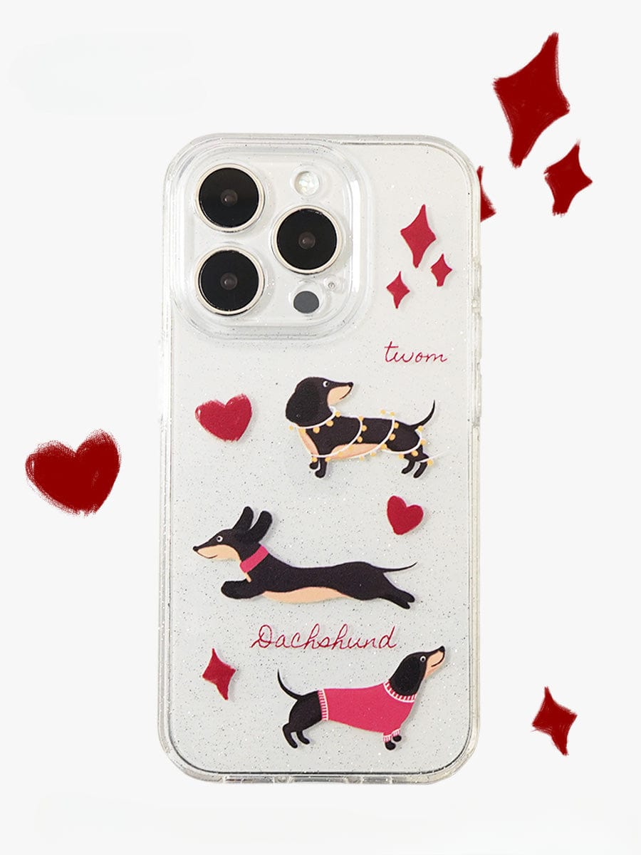 The "Dachshund Love iPhone 16 Pro Max Case | Clear Sparkle Design | Cute All-Inclusive Protective Cover" features charming illustrations of three dachshunds in different poses and outfits. "Dachshund" is written next to one dog, while the name "twom" is placed near the top. Red heart and diamond shapes surround the edges, adding a playful and delightful touch.