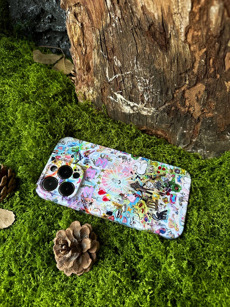 A smartphone adorned with the Whimsical Dreamscape iPhone 16 Pro Max Case - Fantasy-Inspired Artistic Design rests on a bed of vivid green moss next to a pinecone. The background features a large, textured tree trunk, evoking a natural, forest-like setting.