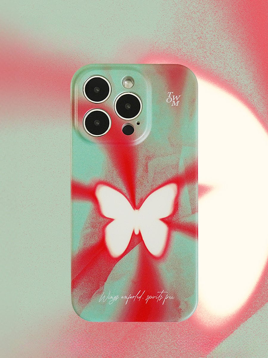 A smartphone with a Butterfly Aura iPhone 16 Pro Max case featuring a white butterfly design on a vivid red and mint green gradient background, adorned with the initials "J.W.M" and a phrase at the bottom.