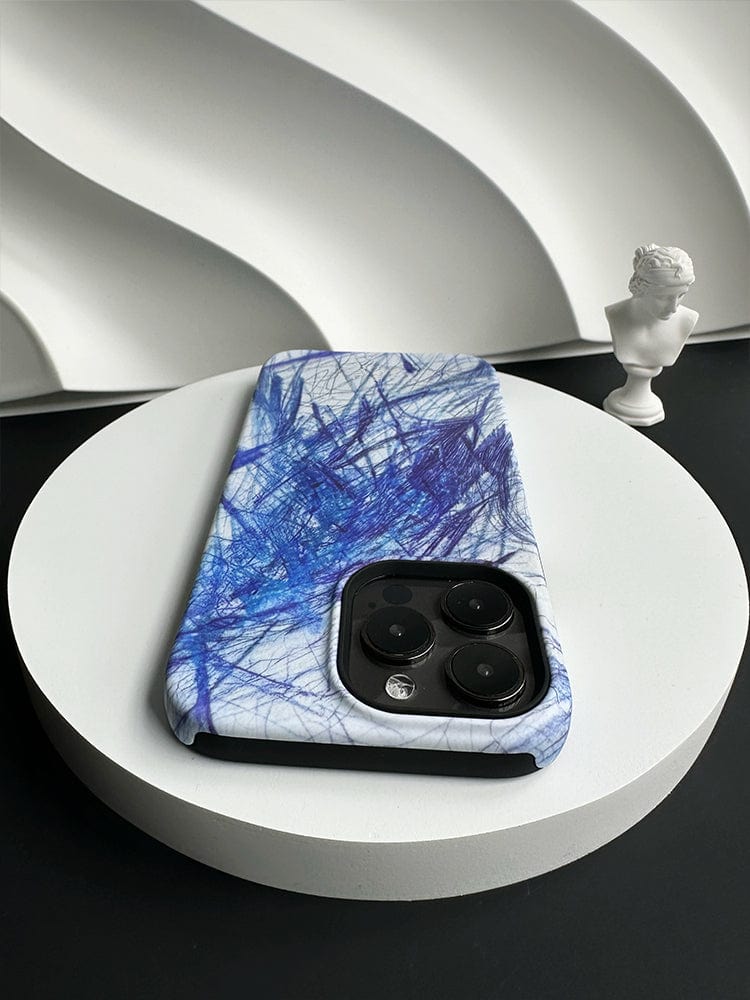 An Abstract Blue Scribble iPhone 16 Pro Max Case - Artistic Design with Full Protection lies on a white circular platform against a textured white background. A small white statue bust is placed on the platform next to the phone.