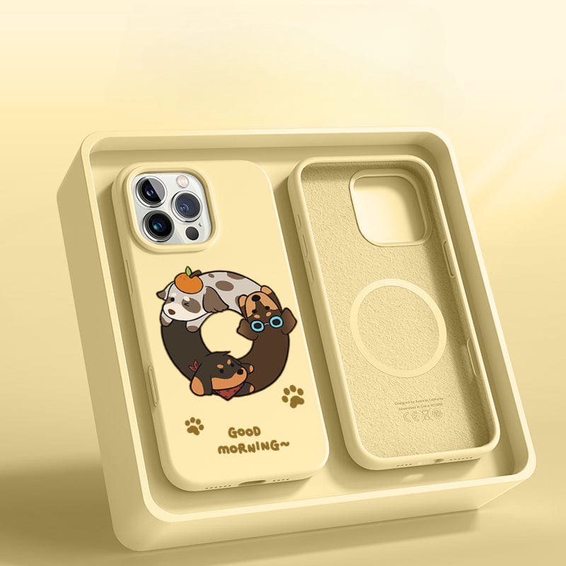 A yellow iPhone 16 Pro Max case, named "Good Morning Cartoon Dog Silicone Protective Cover," is displayed in a light yellow box. This case features adorable cartoon dogs forming a ring and the text "Good Morning," offering triple-layer shockproof protection along with anti-yellowing and a washable design.