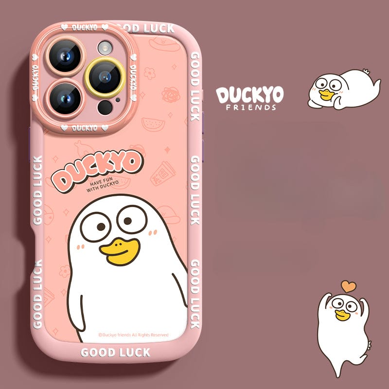 The iPhone 16 Pro Max Yellow Duck Cartoon Case is crafted from soft liquid silicone in a pink hue and features a charming yellow cartoon duck with the text "DUCKYO" and "GOOD LUCK" repeated around the edge. Designed for ultimate shockproof phone protection, it includes cutouts for three camera lenses. The background also includes additional duck illustrations for an extra touch of cuteness.