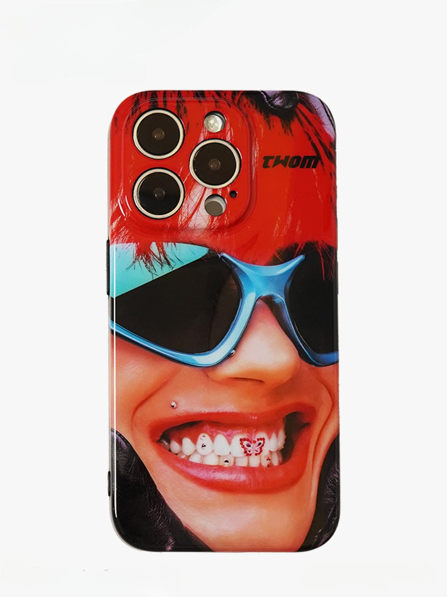 The Bold Rockstar iPhone 16 Pro Max Case features a vibrant, close-up image of a smiling person with a lip piercing, red hair, and large blue sunglasses. The person's teeth are adorned with playful designs against a striking red and black background.