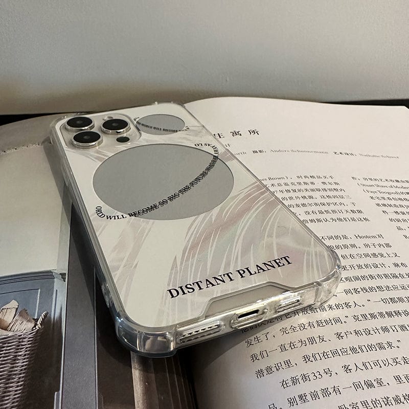 An iPhone 16 Pro Max with a Futuristic Distant Planet case, characterized by its sleek and minimalistic design of grey circles and abstract shapes, rests on an open book featuring text in Chinese. The case prominently displays the phrase "DISTANT PLANET" in black letters.