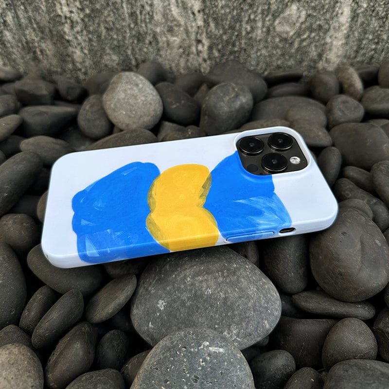 The Abstract Expressionist iPhone 16 Pro Max Case - Bold Blue & Yellow Brushstrokes, featuring a hand-painted design of blue and yellow abstract shapes, encases a smartphone with a sophisticated three-lens camera module, placed elegantly on smooth, dark gray stones.