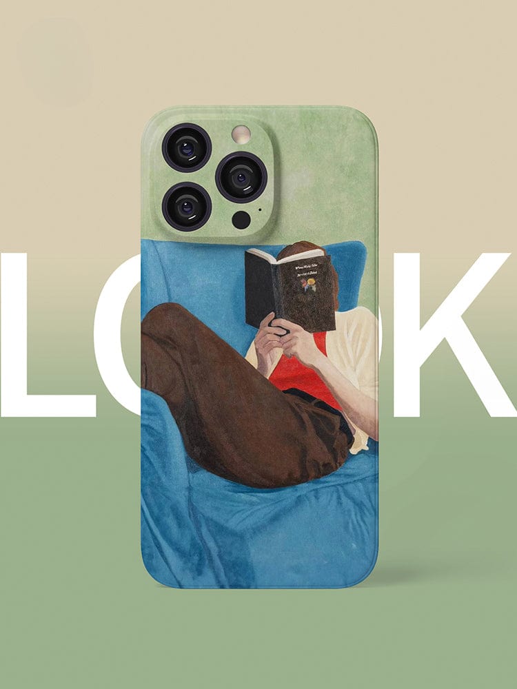 The Relaxed Reader iPhone 16 Pro Max Case - Artistic and Protective showcases a stylish design of a person lounging on a blue couch, engrossed in a book. The background is creatively divided into beige and green sections, with bold, partially hidden white text that spells "LOOK.