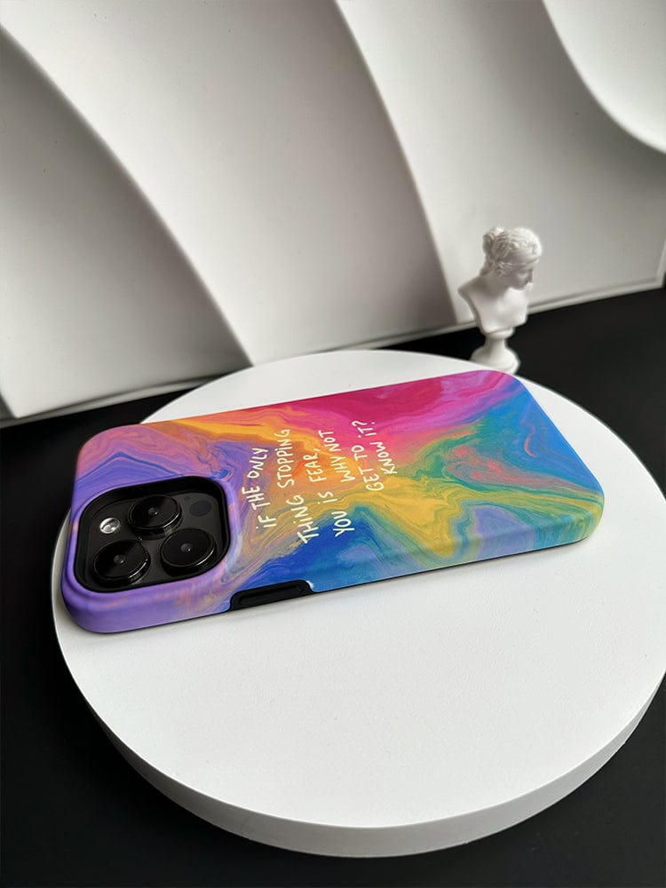 A modern smartphone, fitted with an "Inspirational Swirl iPhone 16 Pro Max Case" featuring a colorful abstract design and the motivational quote, "If you could go back and change things, would you try to change me too?", rests on a black and white surface. In the background, there is a small white bust of a classical figure.