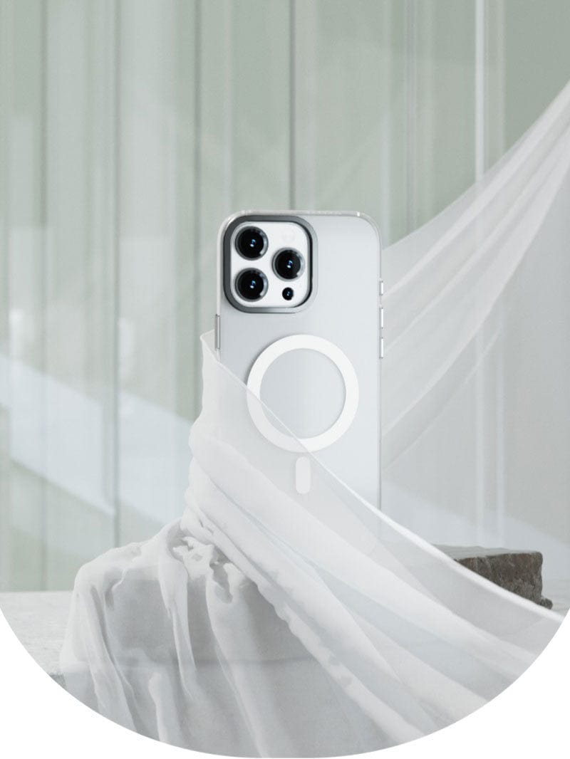 A white smartphone with three camera lenses is displayed with sheer fabric draped around it, set against a light, minimalistic background. Showcased in an iPhone 16 Pro Max Clear Case with MagSafe, featuring an ultra-thin matte finish that ensures long-lasting clarity and protection through its anti-yellowing shockproof cover.