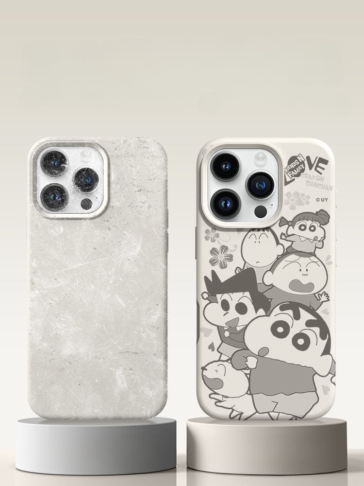 Two smartphones with cases are displayed on stands. The left phone case, boasting triple-layer shockproof protection, is solid gray with a textured surface. The right phone case, an iPhone 16 Pro Max Crayon Shinchan Friends Case, features characters from Crayon Shinchan on a high-quality liquid silicone white background and offers shockproof and anti-fingerprint protection with a soft touch finish.