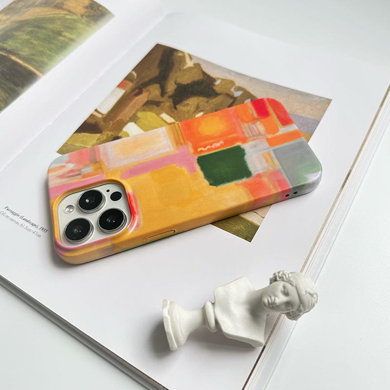 A smartphone with a Modern Abstract Color Block iPhone 16 Pro Max Case - Vibrant Artistic Design with Full Protection rests on an open book featuring a painting. In front of the phone, there is a small white bust statue. The scene is set on a white surface, creating a minimalist and artistic composition.