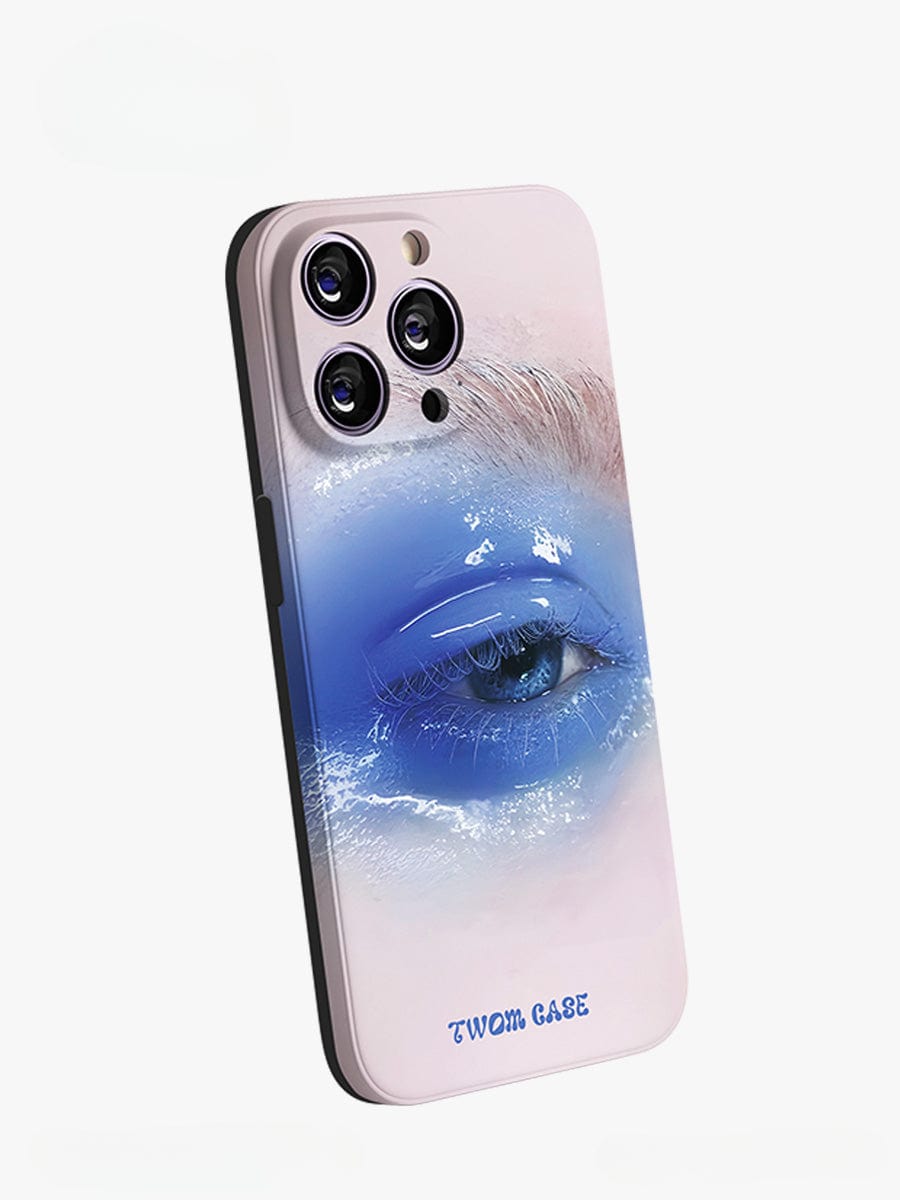 A smartphone with a Dreamy Blue Eye iPhone 16 Pro Max Case, featuring surreal art design of a detailed blue eye surrounded by a gradient of blue and white hues. The elegant all-inclusive protective cover has three large cutouts for the device's cameras along the top and the words "TWOM CASE" at the bottom.