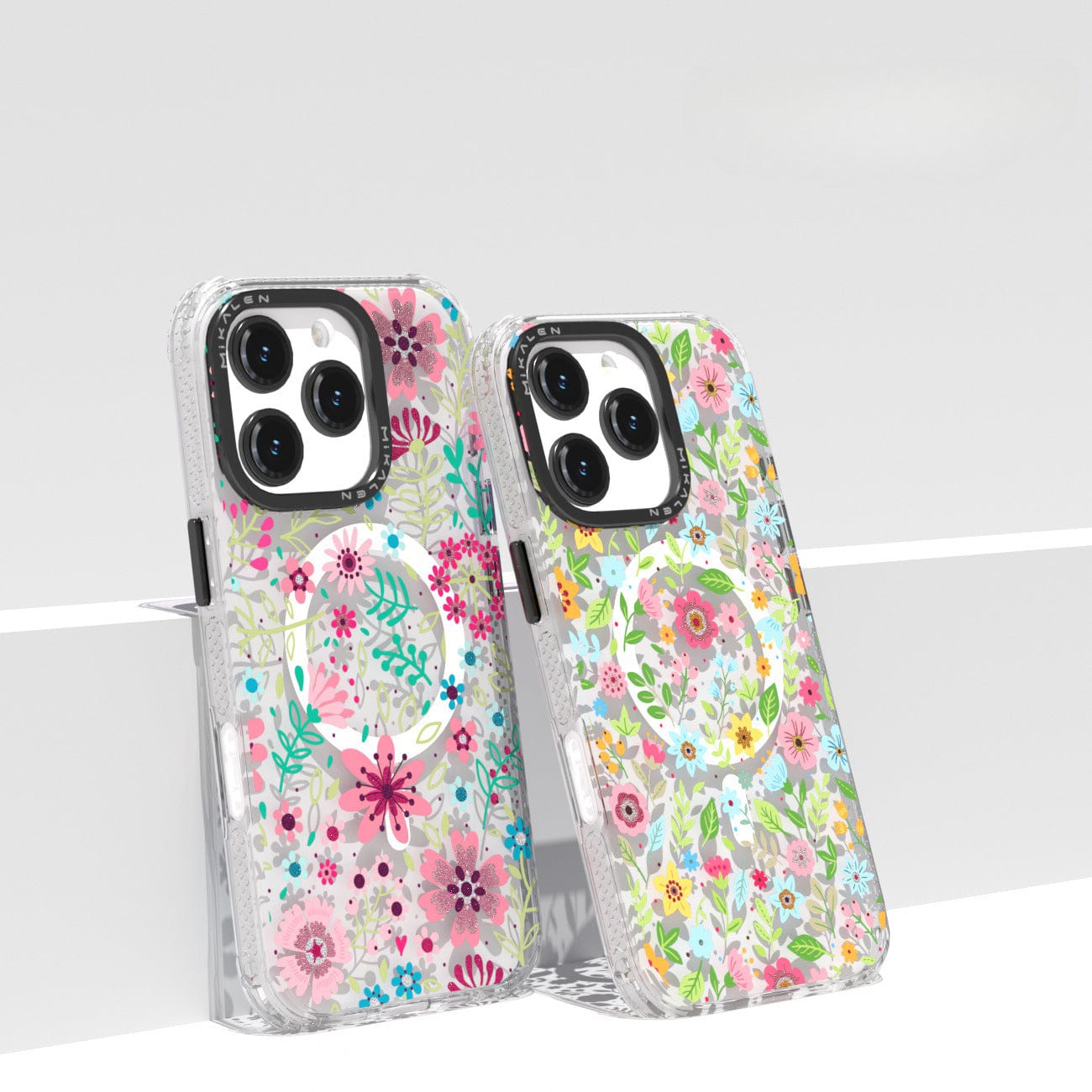 Two Floral MagSafe iPhone 16 Pro Max Cases | Shockproof Clear Cover with 3D Flower Design are displayed side by side on a white surface. Both cases, featuring transparent backgrounds with colorful flowers in pink, green, and blue hues, offer MagSafe compatibility and shockproof protection.