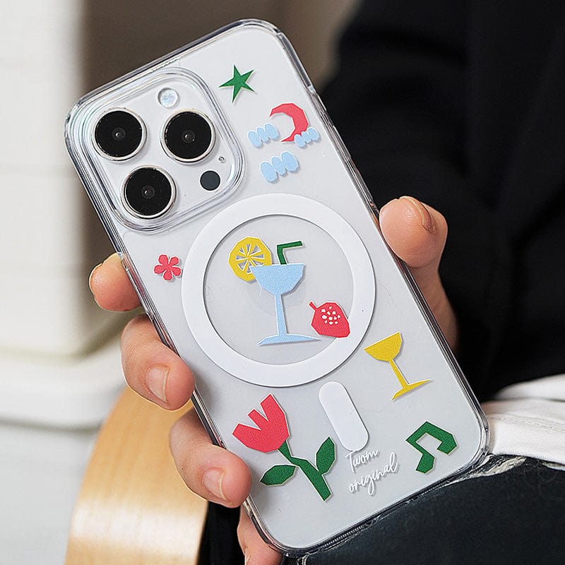 A person holds a Tropical Vibes MagSafe iPhone 16 Pro Max Case, featuring a transparent design adorned with colorful 3D elements including a cocktail glass, strawberry, flower, and musical notes.