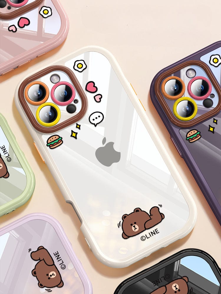 Various iPhone 16 Pro Max cases featuring cute cartoon designs of bears, burgers, and speech bubbles are arranged on a surface. These clear protective covers highlight the camera lenses with colored borders, offering both shockproof protection and an anti-yellowing transparent back.