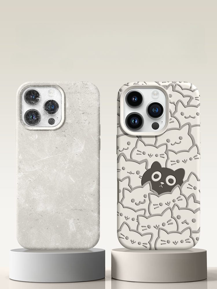 Two smartphones on stands, one in a sleek marble-textured case and the other in an iPhone 16 Pro Max Cute Cat Pattern Case made from premium liquid silicone, featuring multiple cat faces with a standout black cat face in the center.