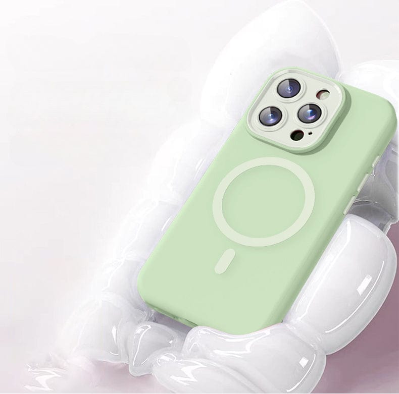 A light green smartphone with a circular design on its back lies on a shiny, translucent surface, encased in an iPhone 16 Pro Max Case - Soft TPU Liquid Silicone MagSafe Protective Cover featuring Nano Cushion Technology.