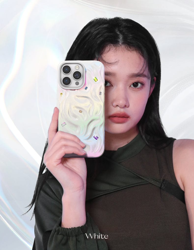 An individual holds an iPhone 16 Pro Max Luxury Case featuring a handcrafted gemstone design and made from impact-resistant PC material in front of their face, while the glossy, abstract white background enhances the polished ambiance.