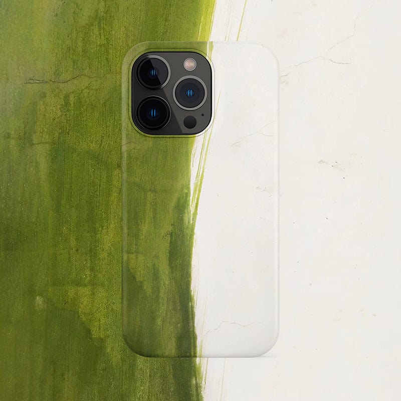 An iPhone 16 Pro Max, sleekly encased in a Minimalist Green Brushstroke iPhone 16 Pro Max Case with an artistic abstract design, rests on a surface with a blurred green and white background. The phone's triple camera system on the back is prominently visible.