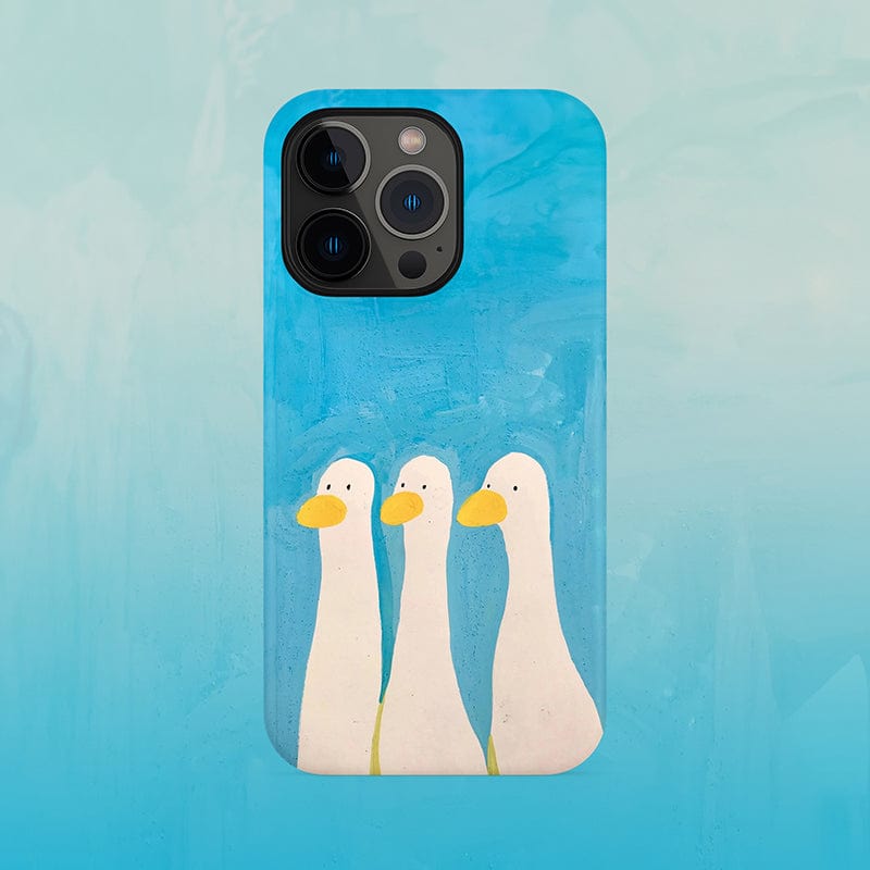 The "Whimsical Three Ducks iPhone 16 Pro Max Case" features a playful blue background with an illustration of three white ducks standing in a row, each adorned with a yellow beak. The ducks are rendered in a minimalistic and whimsical style. This ultra-slim case offers full protection while keeping the phone camera and buttons unobstructed.