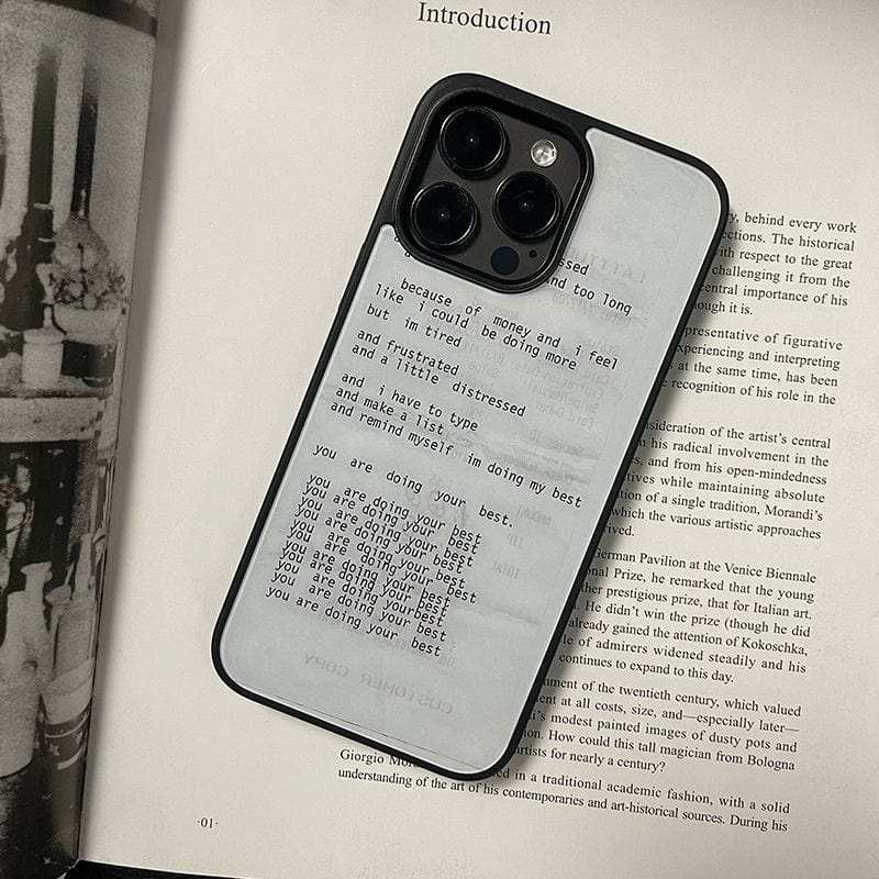 An iPhone 16 Pro Max encased in the Affirmation Script - Minimalist Design with Positive Vibes case, featuring a motivational poem in black text on a gray background, rests on an open book. The poem offers reassurance and encouragement to the reader. The phone, with its triple camera setup, is positioned slightly off-center.