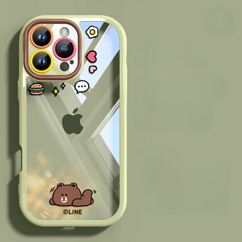 The iPhone 16 Pro Max Case - Cute Cartoon Clear Protective Cover with a Shockproof Bumper and an Anti-Yellowing Transparent Back features light green color and cartoon design stickers of a bear, a speech bubble, a burger, a flower, a heart, and stars. The reflection in the shockproof case shows a window and lights.