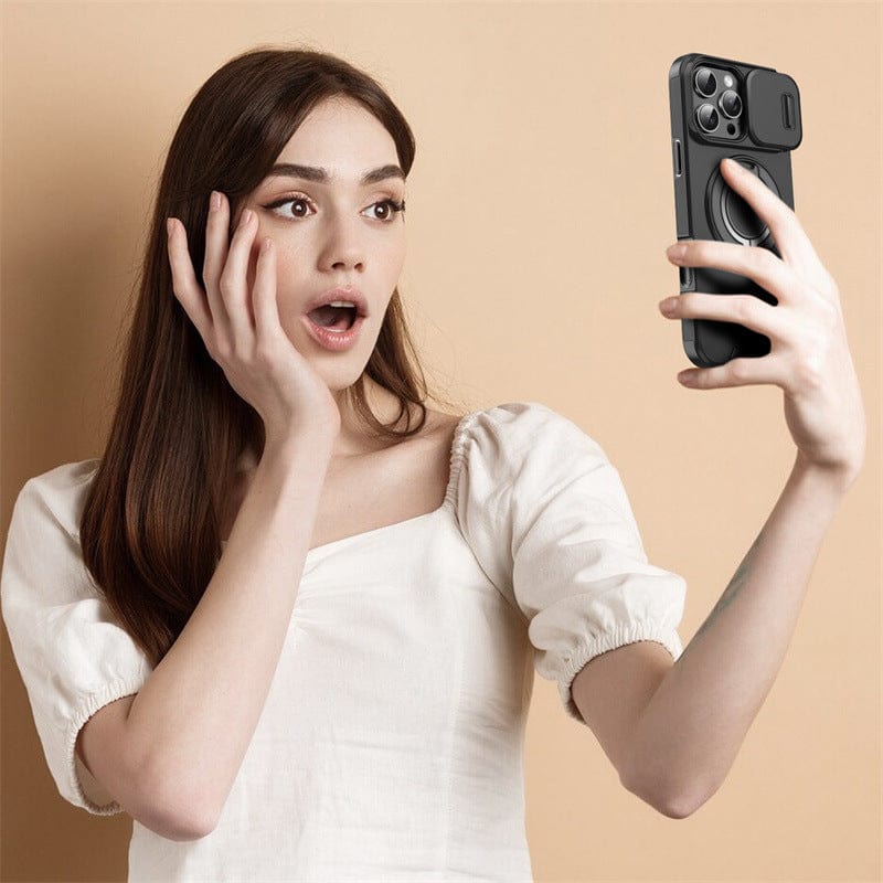 A woman with long brown hair, wearing a white top, appears surprised as she looks at her smartphone equipped with the iPhone 16 Pro Max Case - MagSafe Compatible with Sliding Camera Cover and Shockproof Airbag Protection while taking a selfie against a beige background.