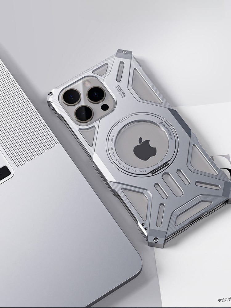 An iPhone 16 Pro Max wrapped in a rugged aerospace aluminum alloy case, equipped with cutouts for the camera, MagSafe compatibility, and a 360° ring kickstand for extra shockproof protection sits beside a silver laptop.