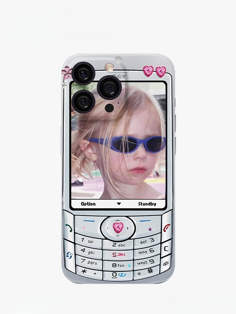 An iPhone 16 Pro Max encased in a Retro Flip Phone iPhone 16 Pro Max Case with a Y2K Nostalgia Design, giving it an old-school flip phone appearance. The screen displays a young child with blonde hair and blue sunglasses, while the case itself is adorned with heart and angel wing decorations near the top and bottom for a fun all-inclusive protective cover.