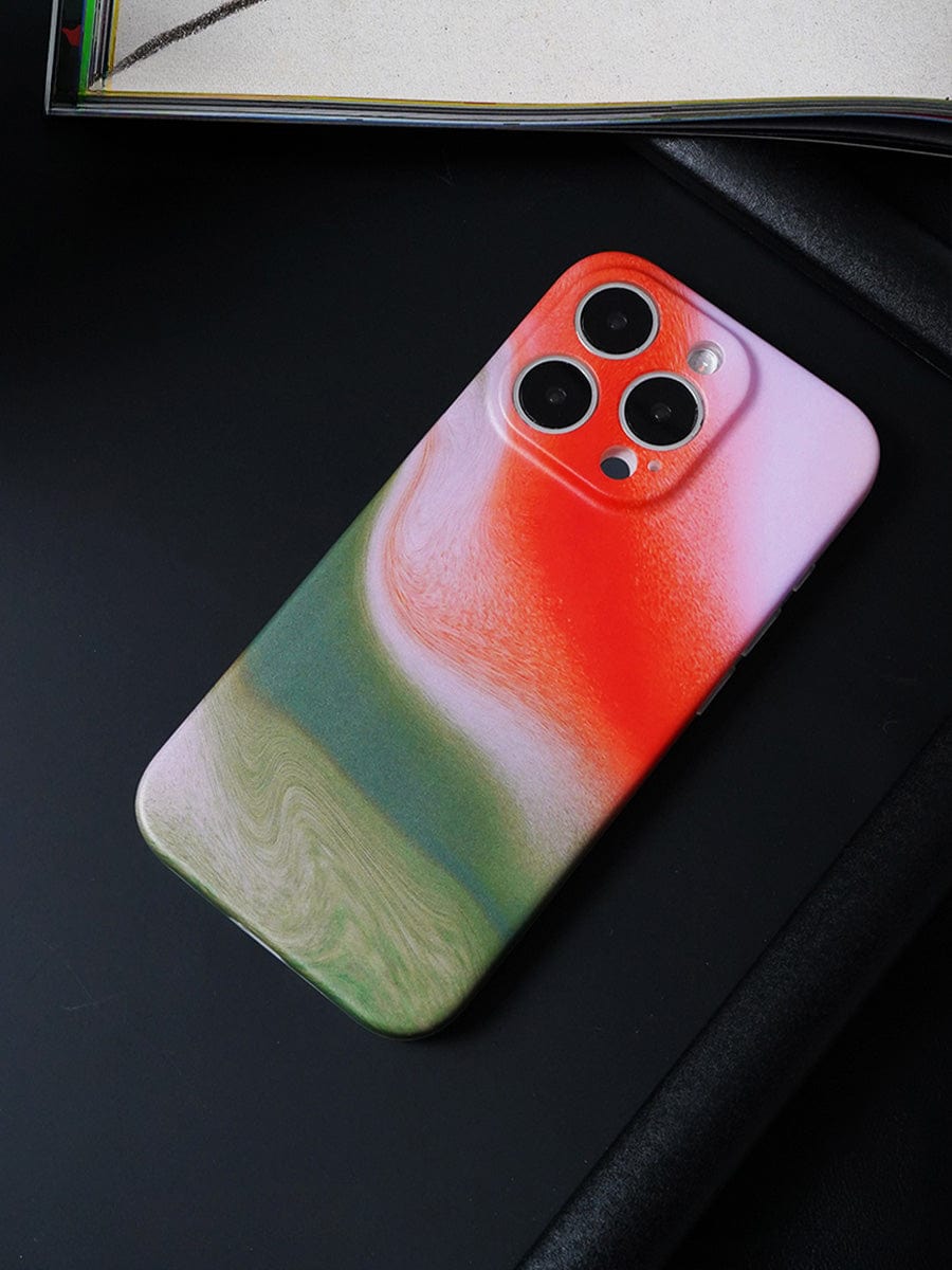 Placed on a black surface is the Sunset Swirl iPhone 16 Pro Max Case, boasting an abstract gradient design with vibrant red, white, and green hues.