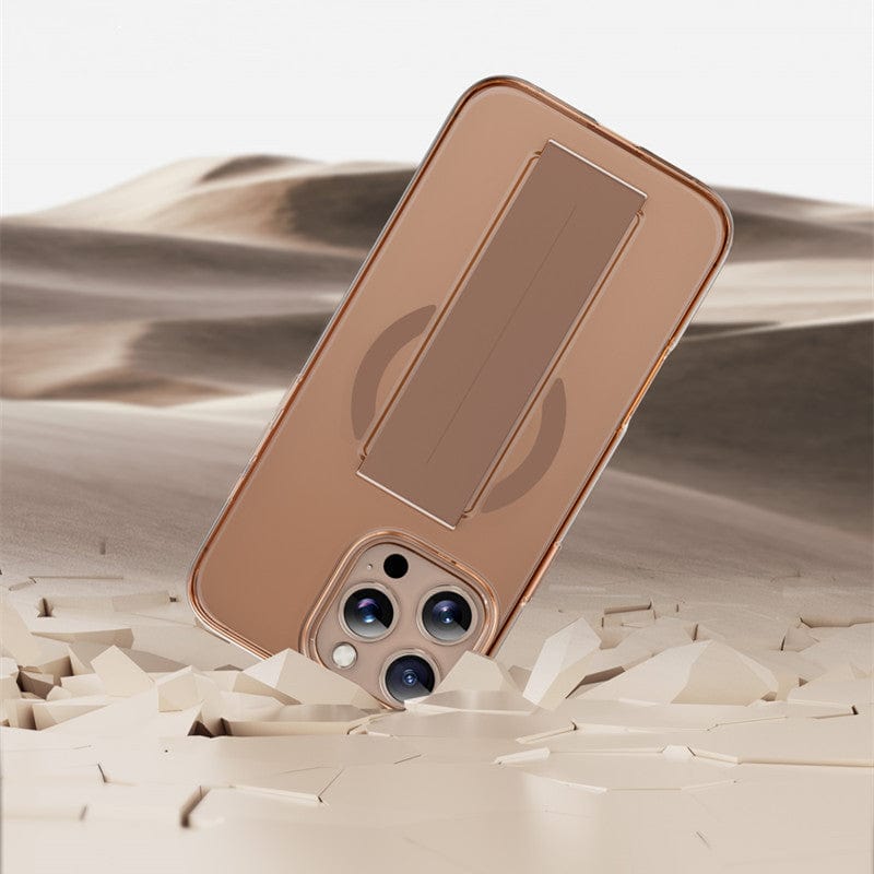 An iPhone 16 Pro Max with a Military-Grade MagSafe Case partially embedded in desert sand, showcasing three camera lenses and offering military-grade protection through its Shockproof Clear Protective Cover with Silicone Grip Strap.