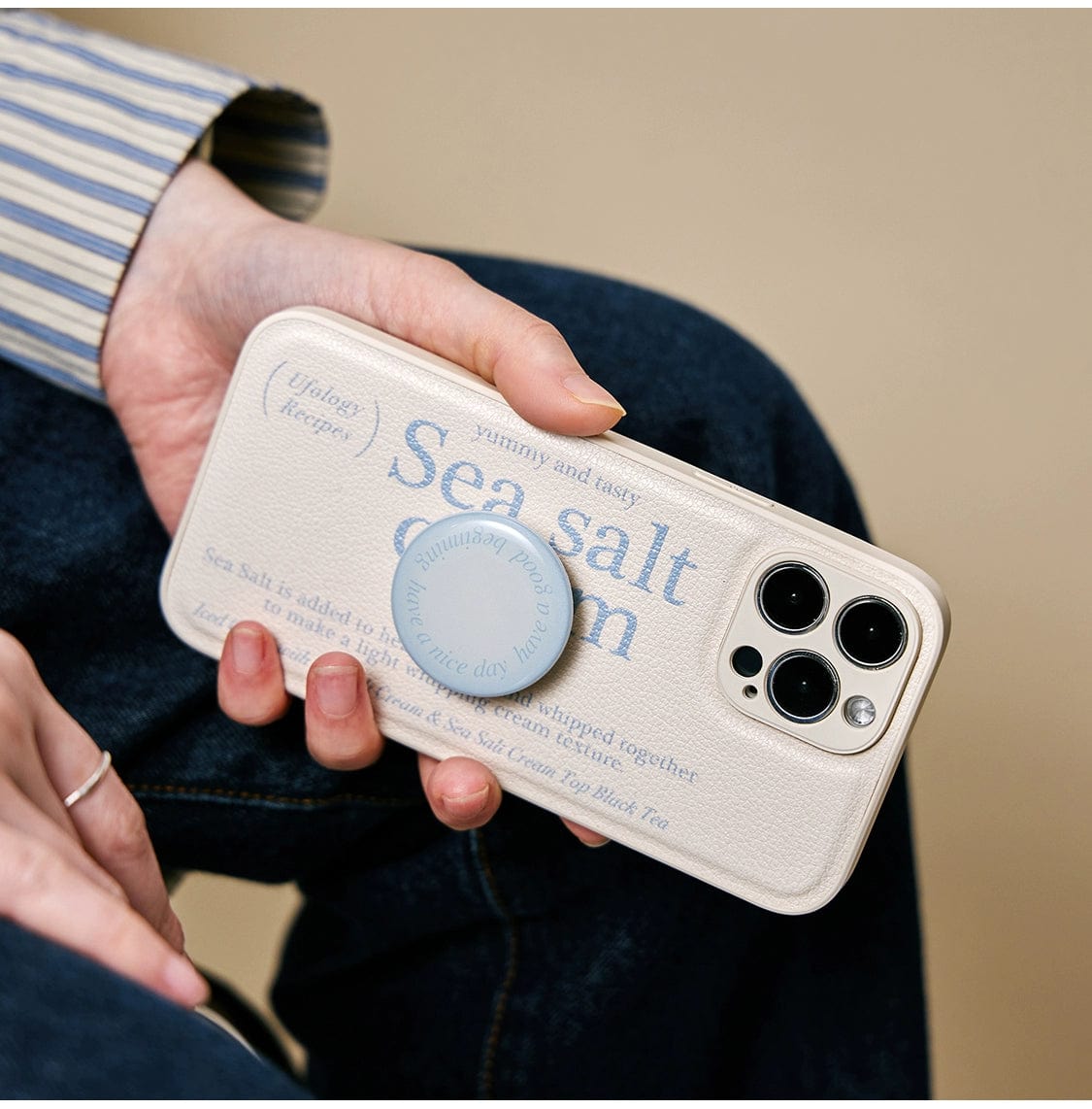 A hand holds a smartphone with a Sea Salt Cream MagSafe iPhone 16 Pro Max Case, showcasing its minimalist textured design and integrated stand.