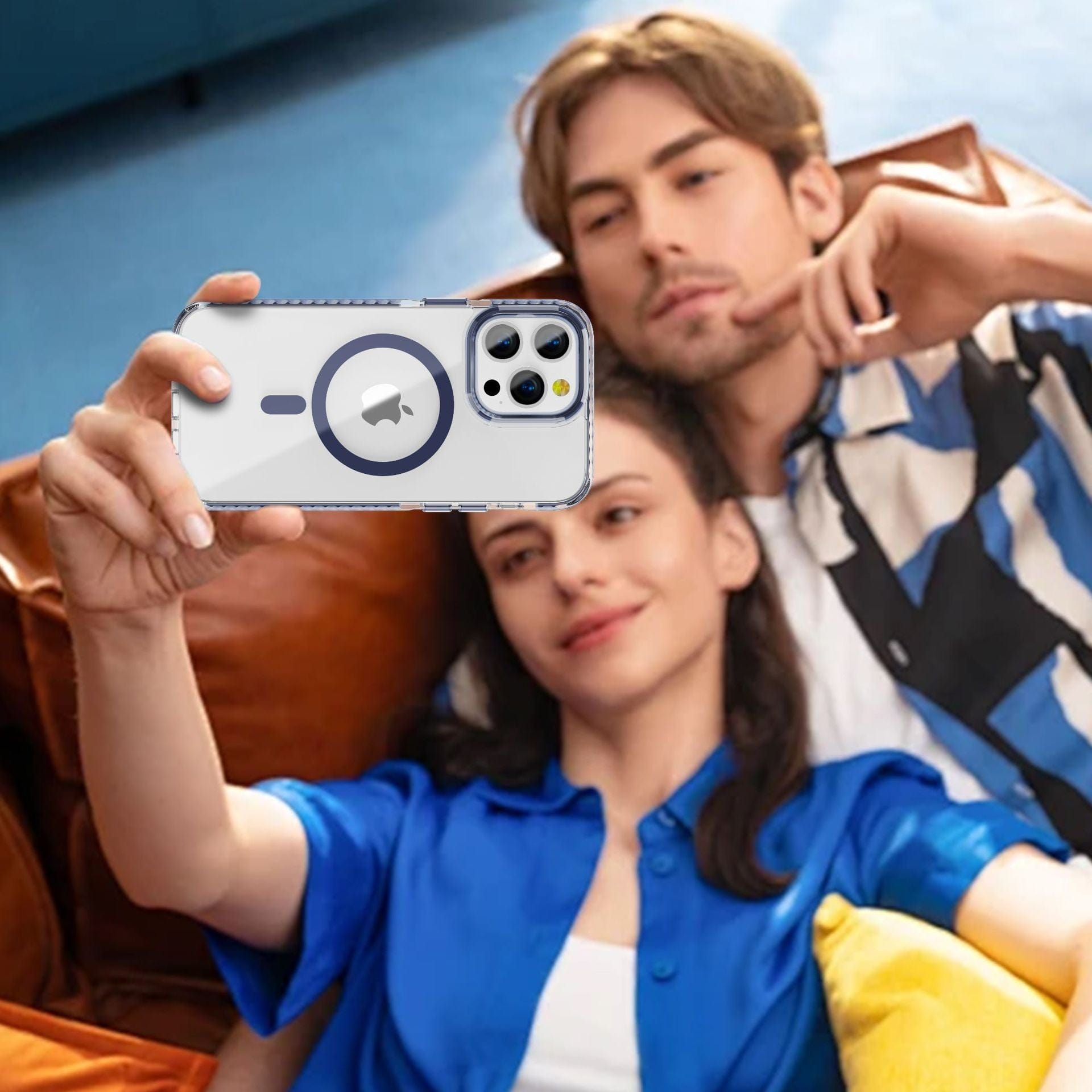 A man and a woman are sitting on a couch, taking a selfie with an iPhone 16 Pro Max. The phone is protected by an iPhone 16 Pro Max Case featuring an acrylic backplate and TPU frame, showcasing a clear design with circular patterns and a visible Apple logo.