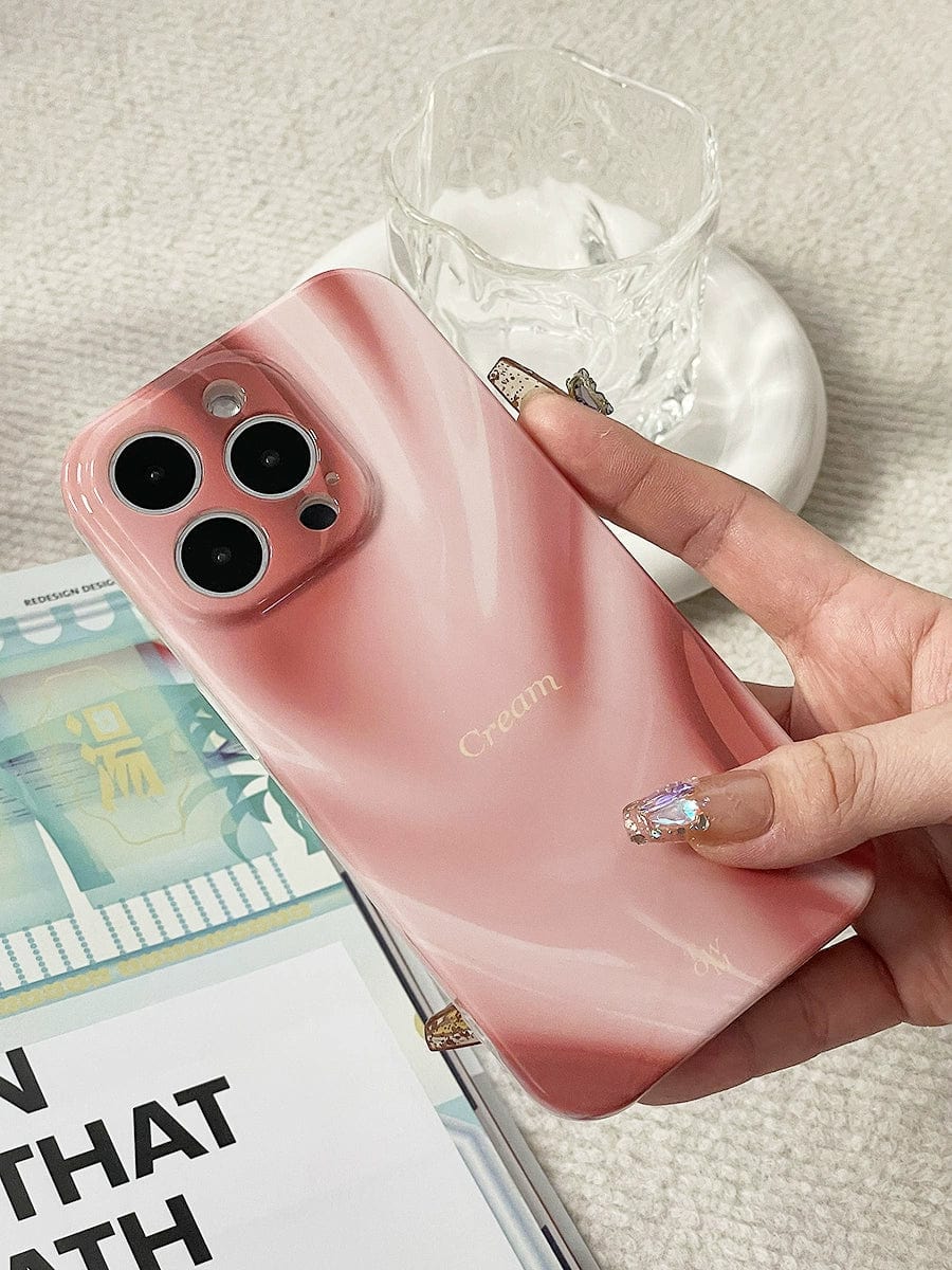 A hand with glittery, decorated nails is holding a Silky Rose iPhone 16 Pro Max Case with an elegant marble design and luxurious all-inclusive protective cover. The phone is next to an open book or magazine and a glass dish containing a frothy beverage.