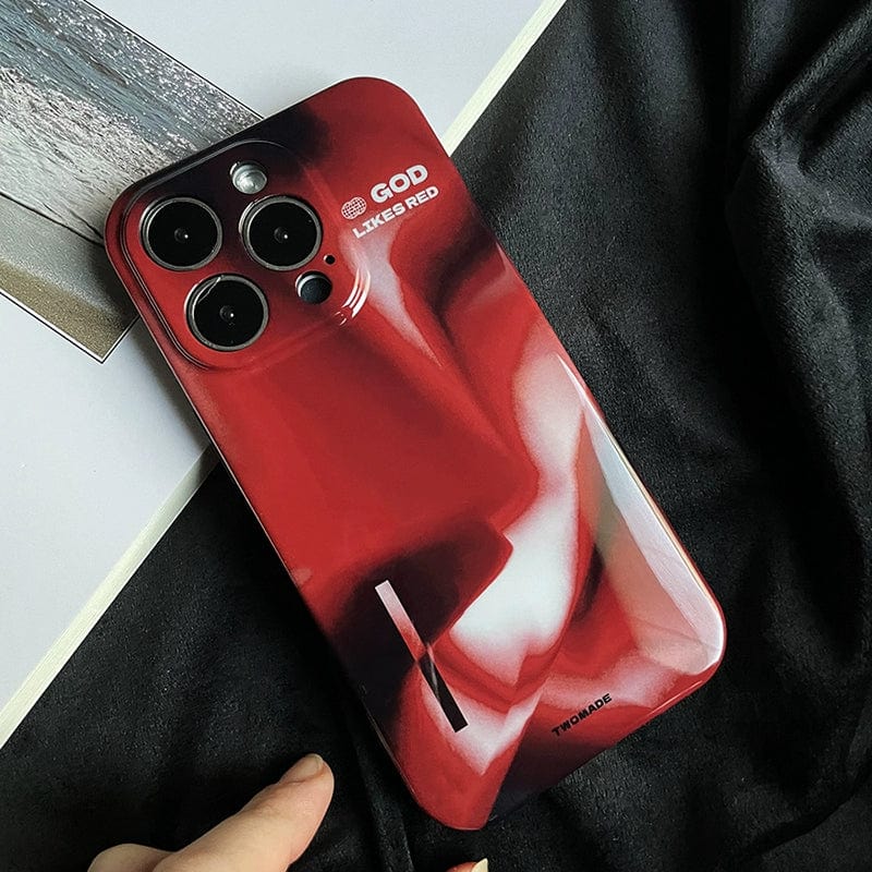 A premium all-inclusive protective cover for the iPhone 16 Pro Max, featuring a bold abstract design in red and black with three rear camera lenses visible, is shown on a dark surface. The case has "GOD LIKE RED" and "TWOMADE" printed on it. A person's hand is partially visible, touching the bottom edge of the phone.