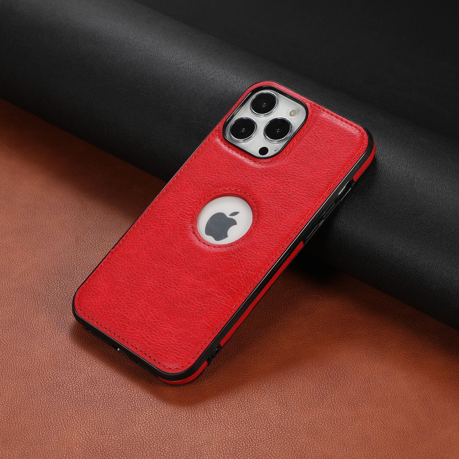 iPhone 16 Pro Max Case - Premium Synthetic Leather, Shockproof, Anti-Fingerprint Protective Cover in red with a black border and a circular cutout revealing the Apple logo, placed on a black and brown textured surface.