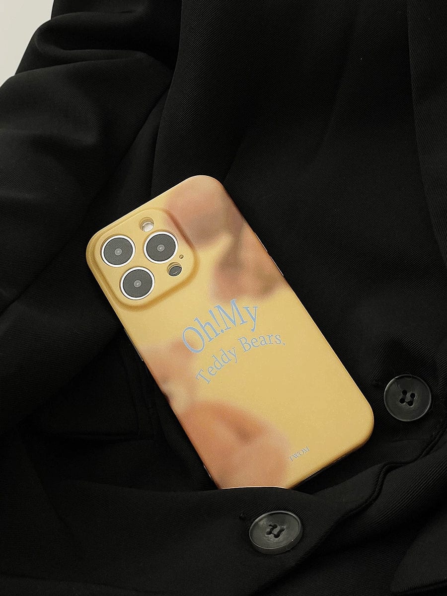 A cream-colored iPhone 16 Pro Max with a three-camera setup is placed on black fabric, encased in an "Oh! My Teddy Bears" iPhone 16 Pro Max Case, featuring a soft matte finish and a cute all-inclusive protective cover. The phone case displays the text "Oh!My Teddy Bears." with a blurred image in the background.