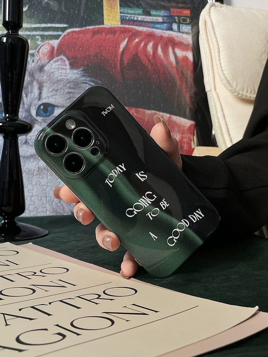 A hand holds an iPhone 16 Pro Max with a "Good Day Quote" case in a sleek dark green design that reads "Today is going to be a good day" in white text.