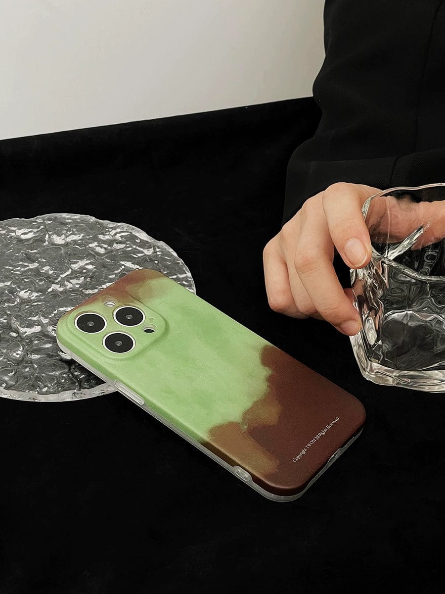 A person holding a clear glass tumbler with ice is resting on a dark surface next to the Midnight Galaxy iPhone 16 Pro Max Case | Cosmic Starry Design | Premium All-Inclusive Protective Cover. The hand is poised as if placing or picking up the glass.