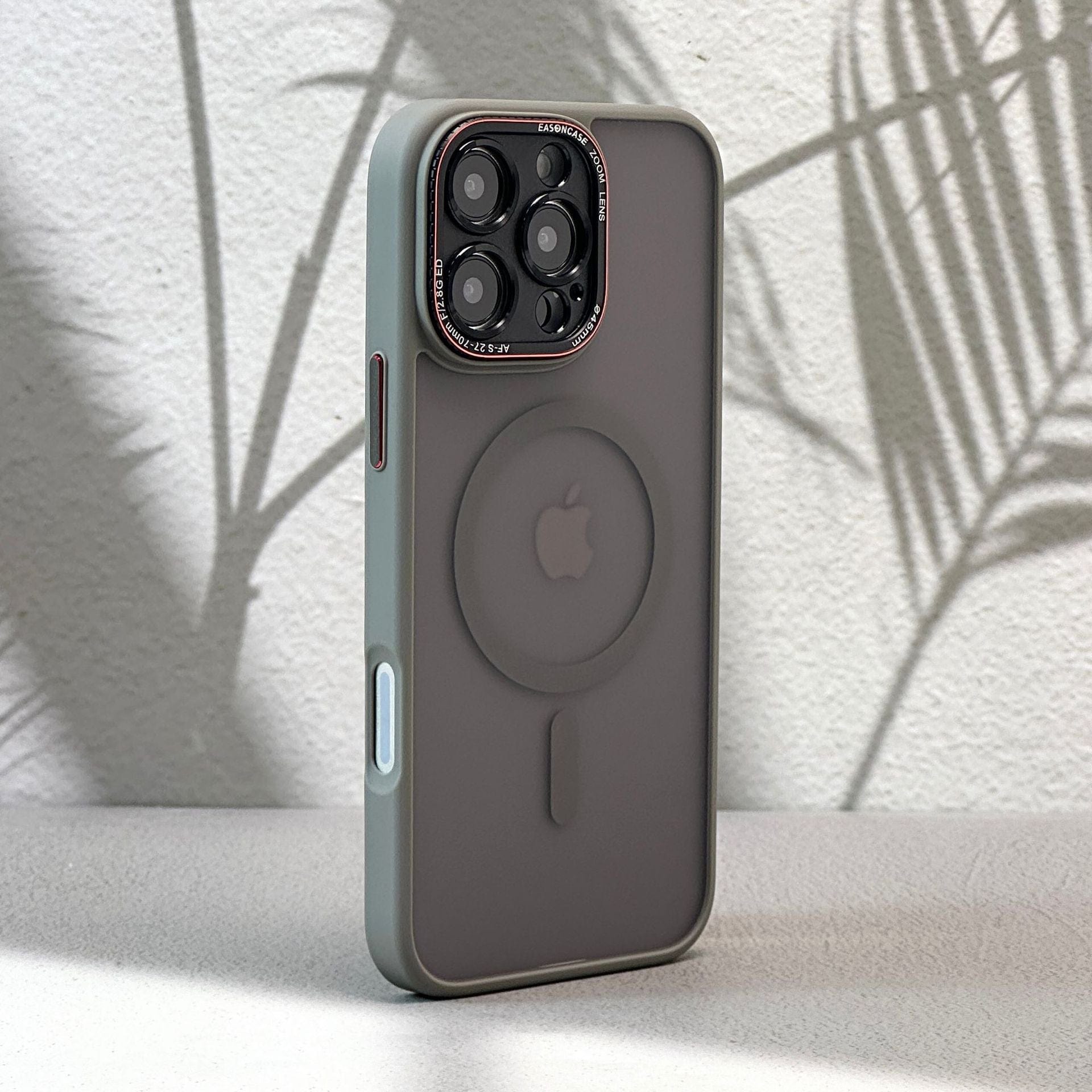 A sleek iPhone 16 Pro Max, encased in a matte finish, shockproof full-coverage case with MagSafe compatibility, stands upright on a surface while shadows of leaves dance on the wall behind it.