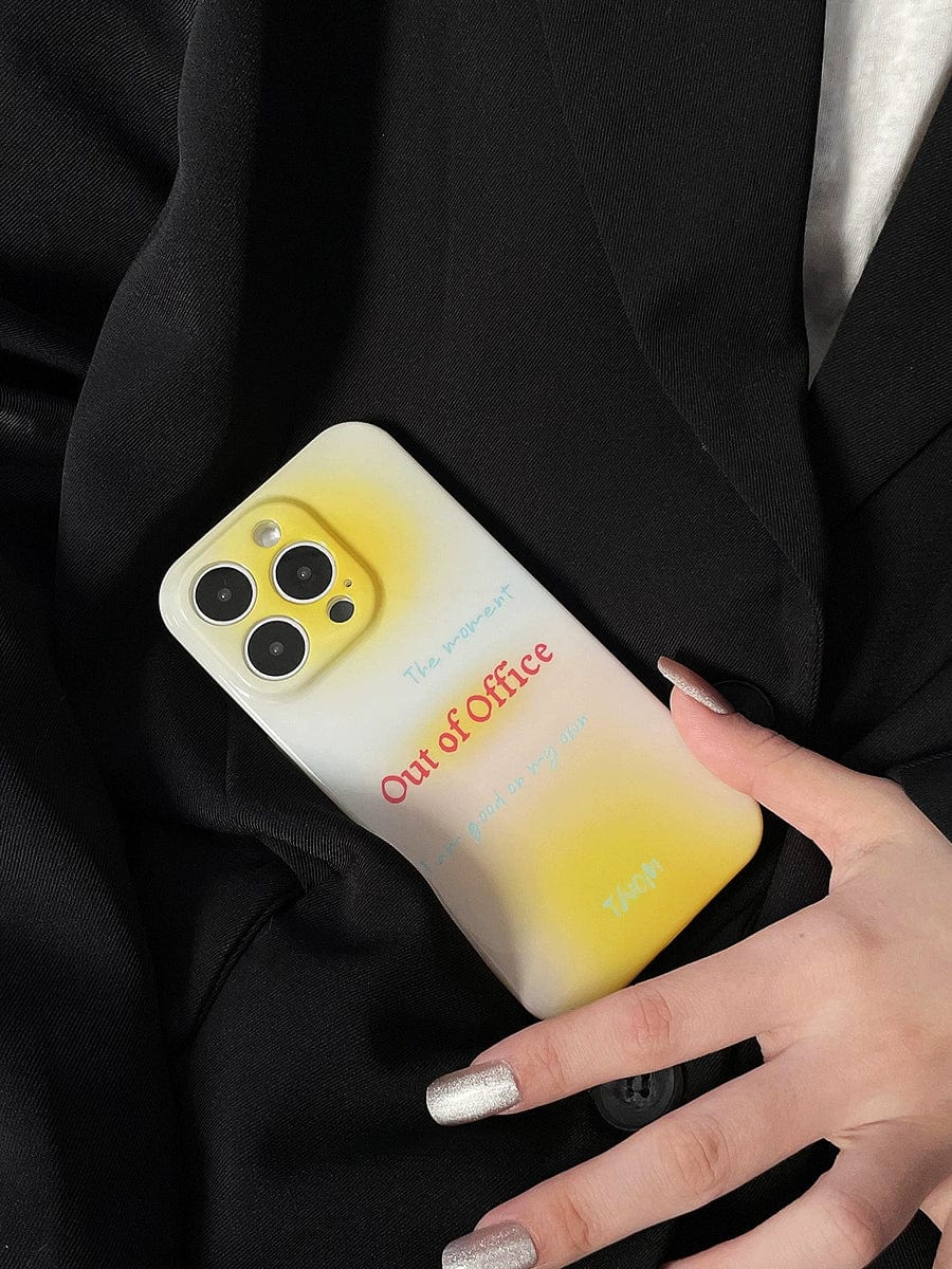 A person holding an iPhone 16 Pro Max with the "Out of Office" Gradient Yellow Design case, a stylish all-inclusive protective cover, that features additional small texts. The person has long, metallic nail polish and is wearing a black outfit.