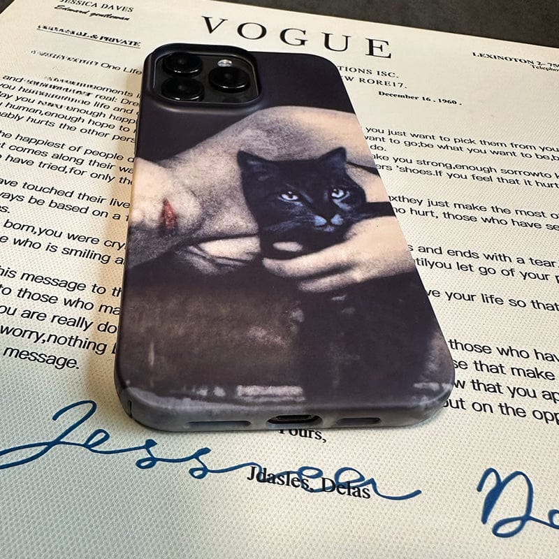 A smartphone with an **Artistic Portrait iPhone 16 Pro Max Case - Vintage Black Cat and Woman Design, Ultra-Slim, Full Protection** featuring a black-and-white image of a person holding a black cat is placed on top of a Vogue magazine. The magazine has a visible signed letter addressed to Jessica at the bottom.