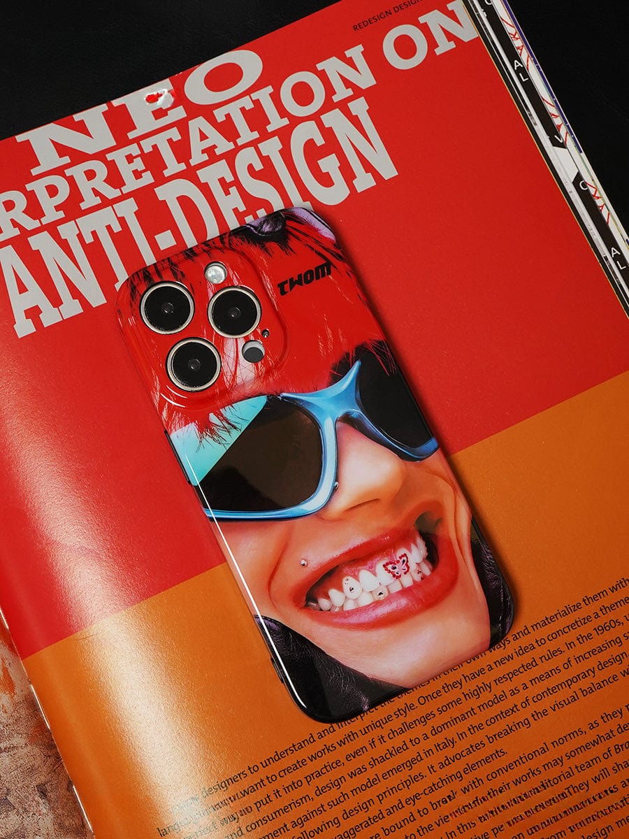 A smartphone with a Bold Rockstar iPhone 16 Pro Max case featuring a vibrant pop art design of a person smiling and wearing sunglasses rests on an open magazine page titled "Interpretation of Anti-Design" in bold text.