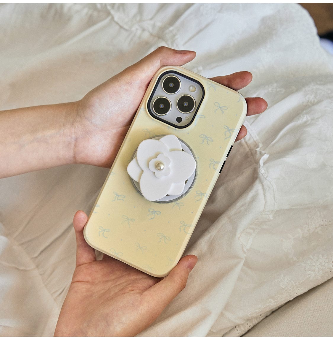 A person holds a smartphone with an Elegant Blossom MagSafe iPhone 16 Pro Max case, displaying chic pastel floral designs and a pearl flower-shaped stand.